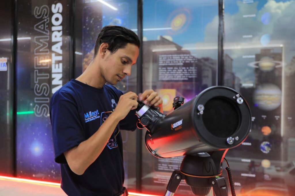 Joven del programa MINCYT ajusta un telescopio en el área de Sistemas Planetarios durante actividades educativas de astronomía.