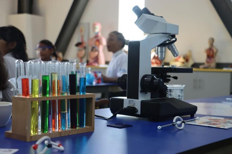 Microscopio y tubos de ensayo con líquidos de colores en un laboratorio del programa Semilleros Científicos del MINCYT en Venezuela.